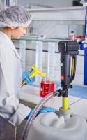 A laboratory technician uses the battery operated Drum pump B2 Battery to transfer chemicals from a Canister into a measuring beaker